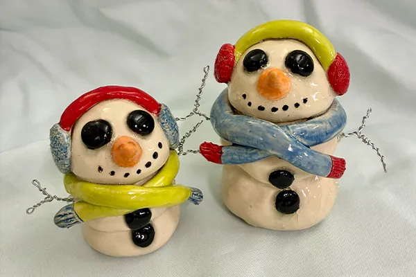 Two handmade ceramic snowmen sculptures with shiny glazed finishes.
