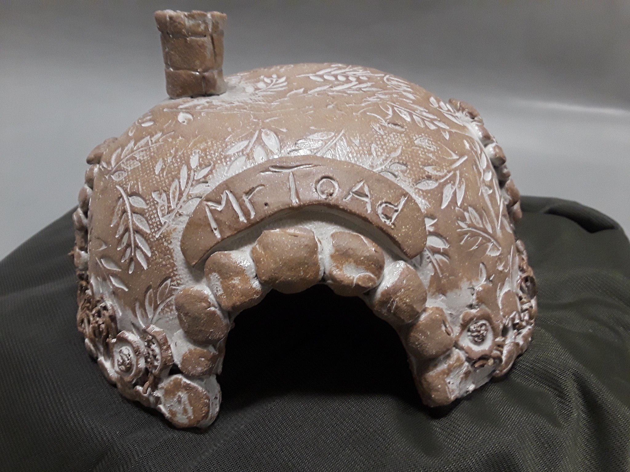 A small ceramic house with a door and window. Sign says "Mr. Toad"