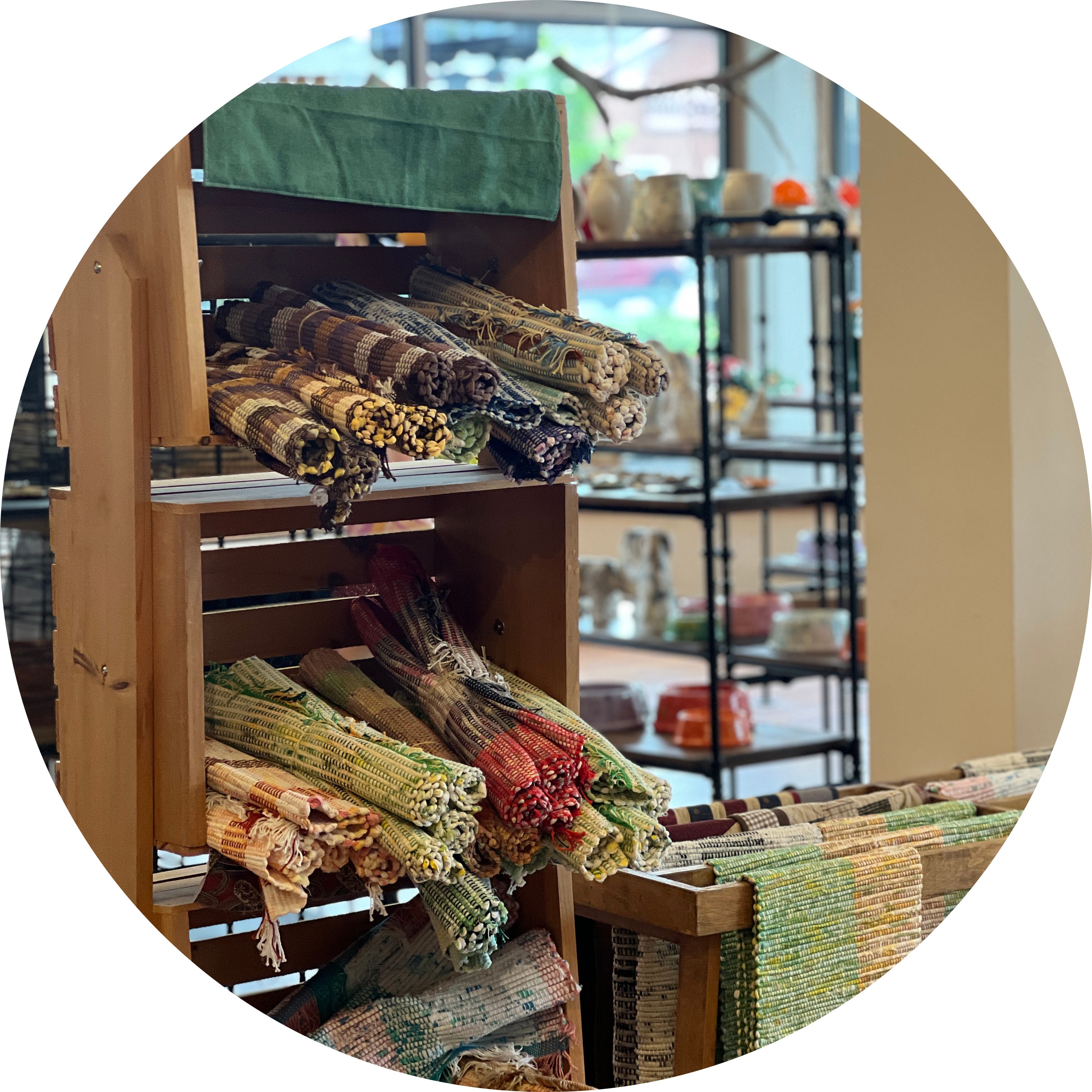 A display of handwoven rugs and textiles in a shop, arranged on wooden racks.