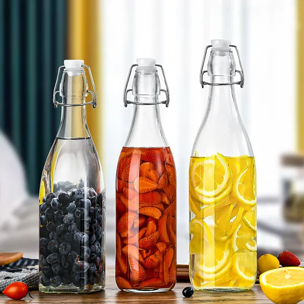 Three glass bottles with swing-top lids are filled with fruit-infused water, displayed on a wooden surface.