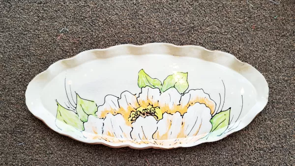 A white flower painted on a plate.