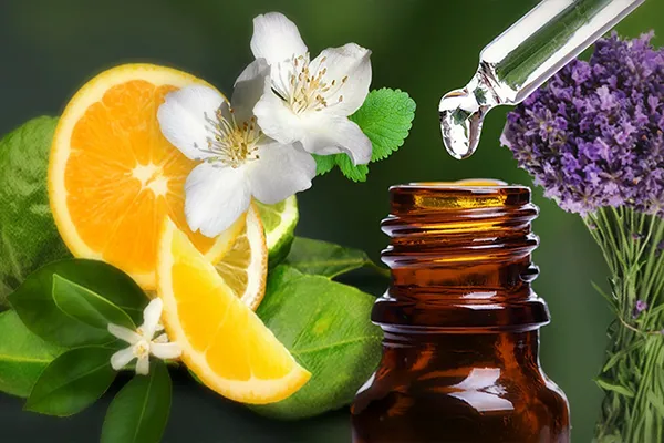 Close-up of an amber glass essential oil bottle with a dropper releasing a liquid drop above it.