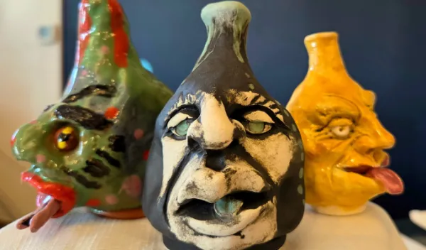 Three whimsical handmade ceramic face jugs with expressive features, colorful glazes, and exaggerated facial details displayed at Sunshine Studios.