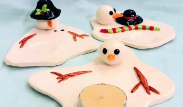 Two handmade ceramic melting snowmen luminaries created during a Sunshine Studios clay class.