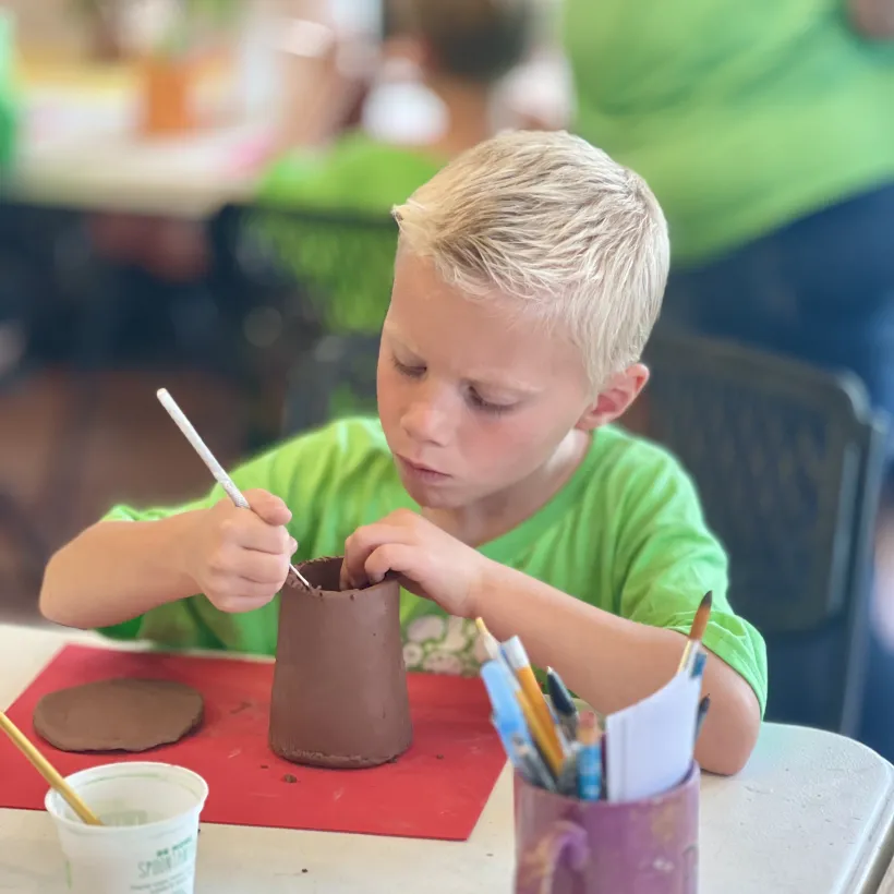 A young boy paints pottery